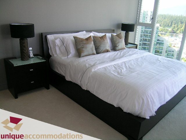 Bright bedroom with city view, modern furnishings, and black bed frame. - 1603-1650 Bayshore Drive, Vancouver Downtown
