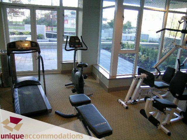 Bright and modern fitness room with large windows, cardio equipment, and weight machines. - 1603-1650 Bayshore Drive, Vancouver Downtown