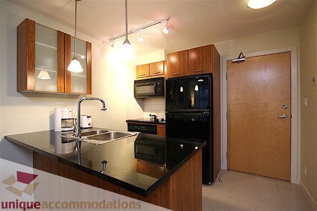 Bright kitchen with modern appliances and wooden cabinets, featuring a stainless steel sink and countertop.