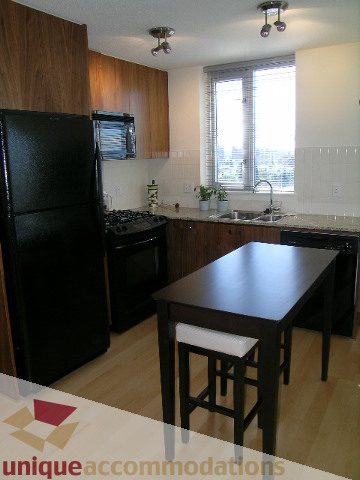 Bright kitchen with dark countertops, hardwood floors, and a city view through the window. - 1204-1030 West Broadway, Vancouver West Side
