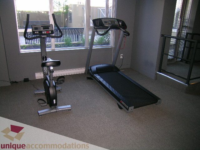 Bright living room with exercise equipment and large windows. - 1204-1030 West Broadway, Vancouver West Side