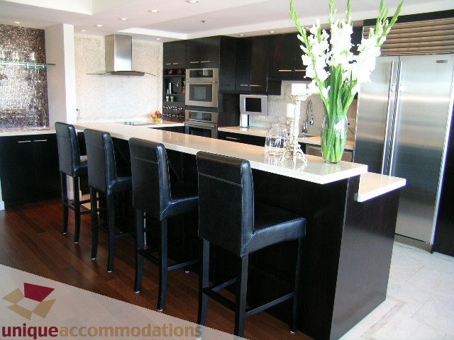 Bright kitchen with modern black bar stools, stainless steel appliances, and hardwood floors. - 602-1012 Beach Ave., Vancouver Downtown
