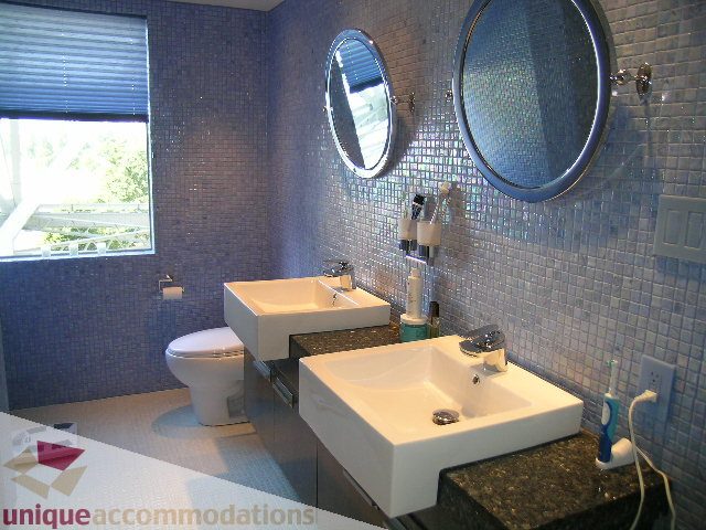 Bright bathroom with mosaic tiles, dual sinks, and a large window offering a city view. - 602-1012 Beach Ave., Vancouver Downtown