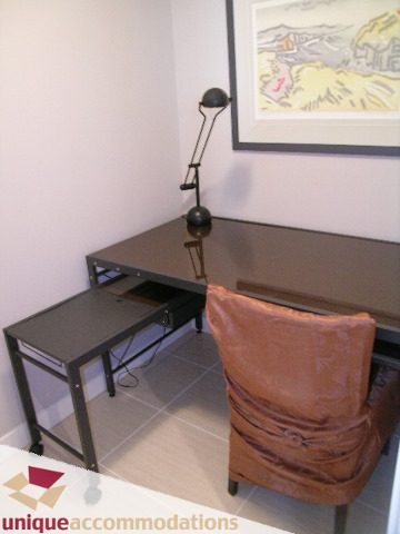 Modern den with sleek black desk, orange armchair, and contemporary artwork. - 103-638 Beach Cres., Vancouver Downtown