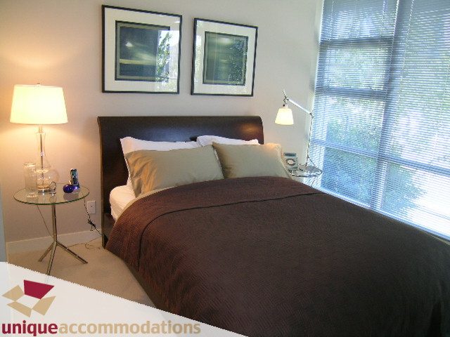 Spacious bedroom with a king bed, modern decor, and a large window with blinds. - 103-638 Beach Cres., Vancouver Downtown