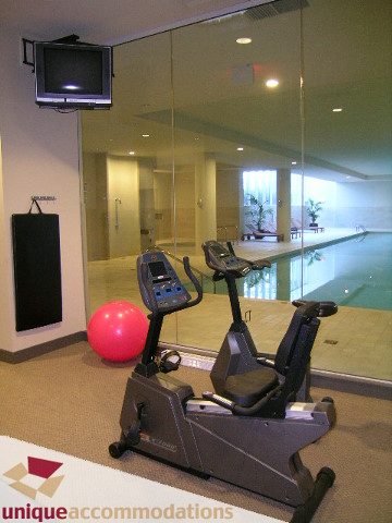 Fitness room with cardio equipment, mirrored wall, and TV, perfect for workout enthusiasts. - 103-638 Beach Cres., Vancouver Downtown