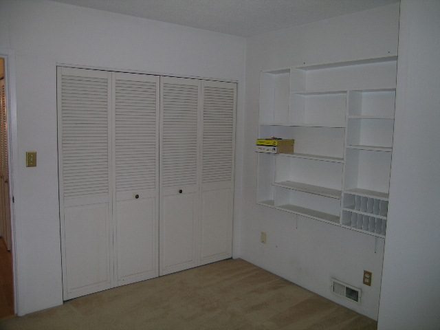 Bright bedroom with white louvered closet doors and built-in shelves. - 147 - 3300 Capilano Rd, North Vancouver