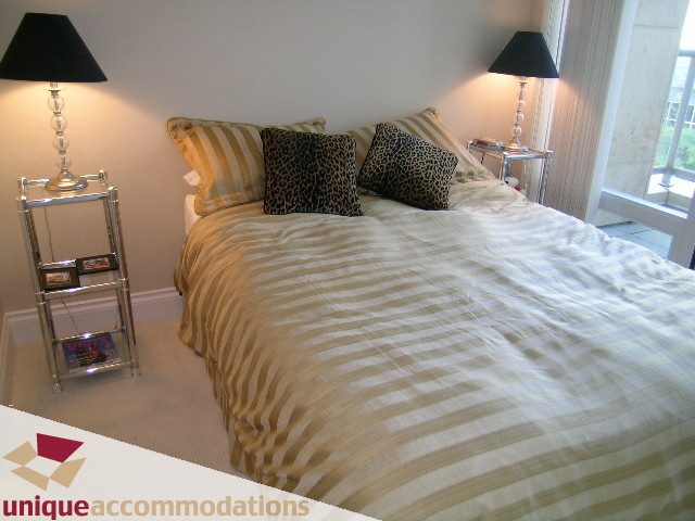 Furnished bedroom with striped bedding and leopard print pillows. - 103 - 1515 Homer Mews, Vancouver Downtown