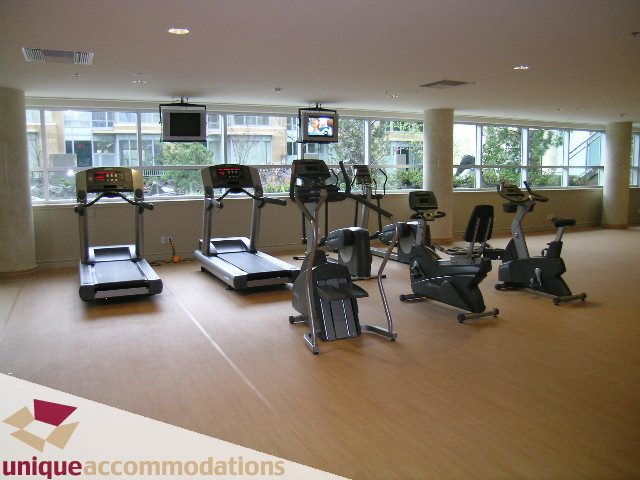 Bright fitness room with hardwood floors, city view, and cardio equipment. - 103 - 1515 Homer Mews, Vancouver Downtown