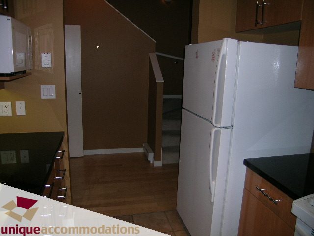 Bright kitchen with white appliances, hardwood floors, and a clean countertop. - 163 Aquarius Mews, Vancouver Downtown