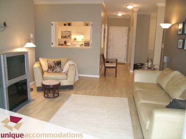 Furnished living room with hardwood floors and a kitchen in the background. - 304 - 1281 Parkgate Avenue, North Vancouver