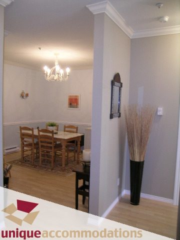 Furnished dining area with wooden chairs and a chandelier, hardwood floors. - 304 - 1281 Parkgate Avenue, North Vancouver