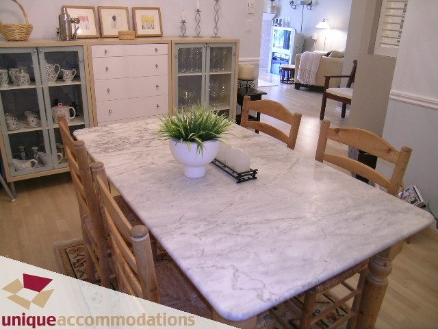 Furnished dining area with marble table, wooden chairs, and glass cabinet. - 304 - 1281 Parkgate Avenue, North Vancouver