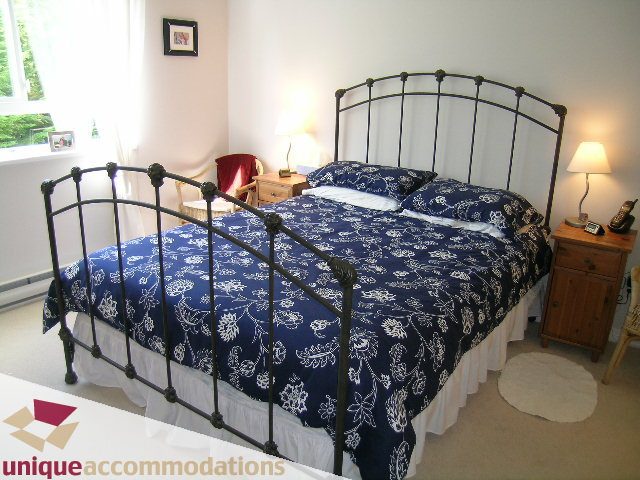Bright bedroom with iron bed frames, blue patterned bedding, and wooden nightstands. - 304 - 1281 Parkgate Avenue, North Vancouver