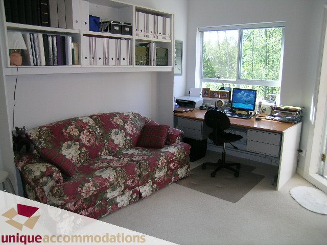 Furnished living room with floral sofa, desk, and large window view. - 304 - 1281 Parkgate Avenue, North Vancouver