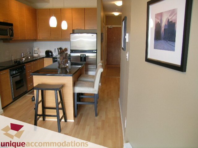 Modern kitchen with stainless steel appliances and hardwood floors, perfect for a cozy 1-bedroom + den condo. - 105 - 530 Raven Woods, North Vancouver
