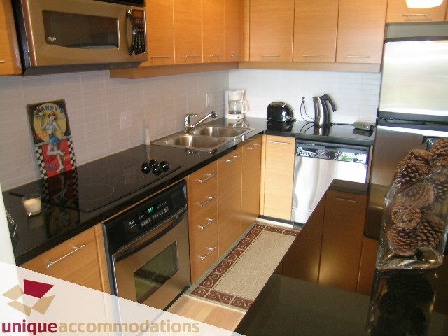 Bright kitchen with stainless steel appliances, granite countertops, and a cozy den featuring a small dining table.