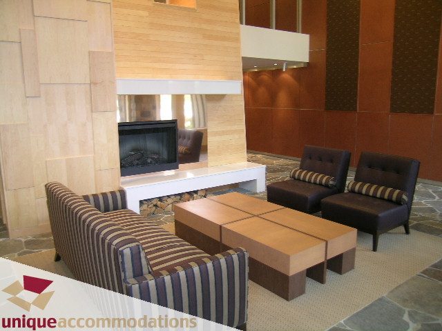 Spacious living room with modern furniture, wood accents, and a cozy fireplace. - 105 - 530 Raven Woods, North Vancouver