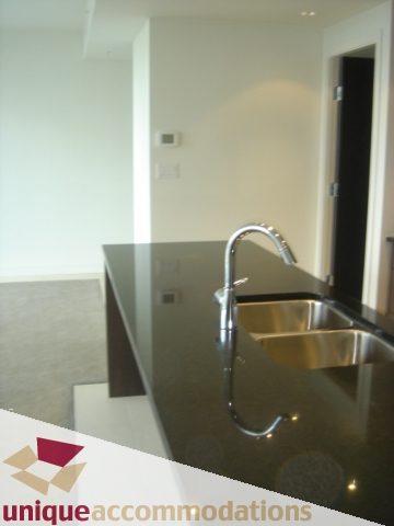 Modern kitchen with sleek black countertops and a stainless steel faucet. - 1101 -1455 Howe Street, Vancouver Downtown