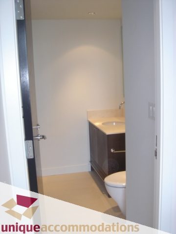 Compact bathroom with modern sink and toilet, featuring a sleek countertop and neutral tones. - 1101 -1455 Howe Street, Vancouver Downtown