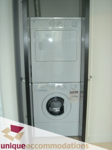 Compact laundry room with stacked washer and dryer, modern design. - 1101 -1455 Howe Street, Vancouver Downtown
