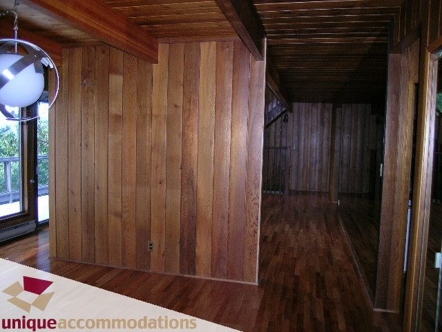 Spacious living room with hardwood floors and wood-paneled walls. - 310 Bayview Road, West Vancouver