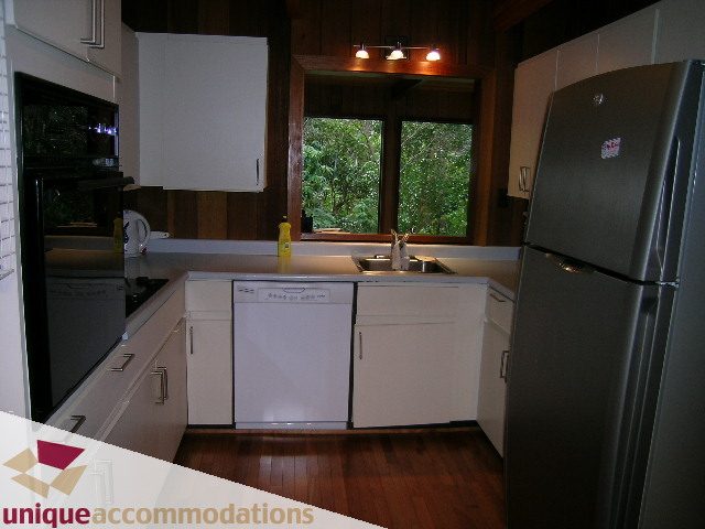 Bright kitchen with white cabinets, hardwood floors, and a view of greenery outside. - 310 Bayview Road, West Vancouver