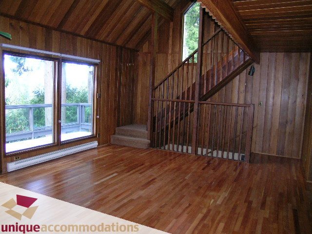 Spacious living room with hardwood floors and large windows, showcasing a city view. - 310 Bayview Road, West Vancouver