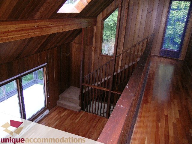 Staircase leading to upper level with wooden walls and large windows. - 310 Bayview Road, West Vancouver