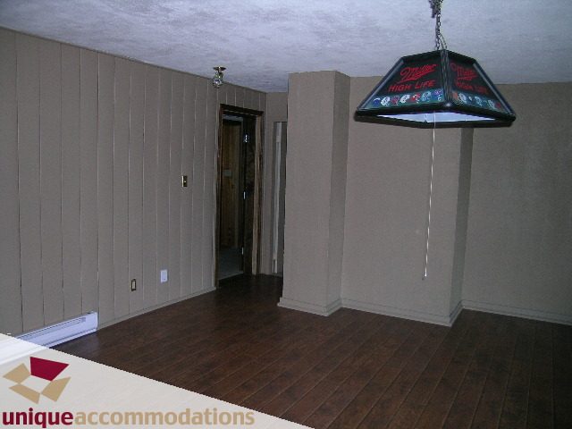 Living room with hardwood floors and a Miller High Life pool table light fixture. - 310 Bayview Road, West Vancouver