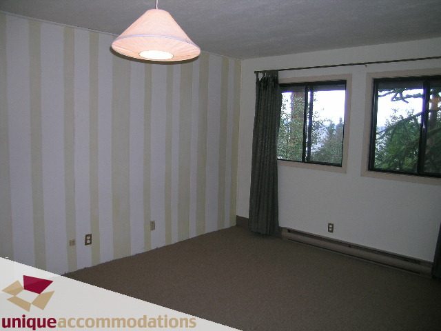 Bright living room with striped wallpaper and large windows showing trees. - 310 Bayview Road, West Vancouver