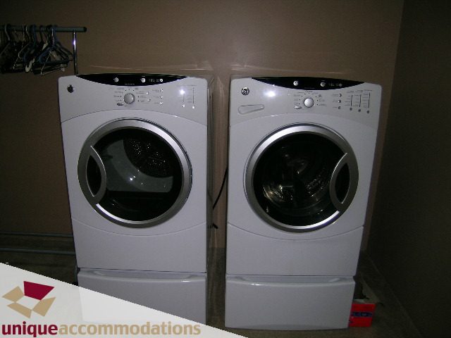 Bright laundry room with stacked washer and dryer, clean and organized. - 310 Bayview Road, West Vancouver