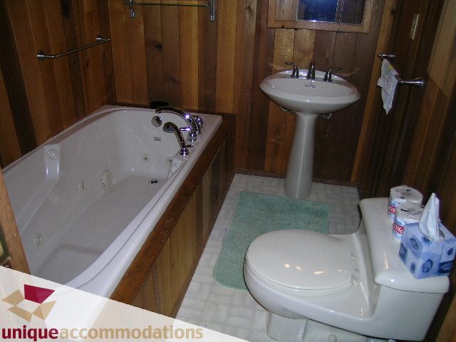 Bathroom with wooden walls, white fixtures, and a green bath mat. - 310 Bayview Road, West Vancouver