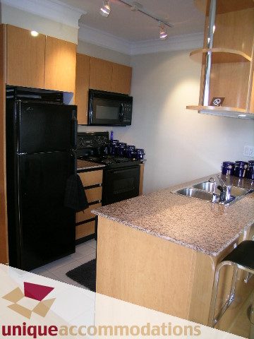 Bright kitchen with granite countertops and black appliances, modern design. - 2606-1189 Howe Street, Vancouver Downtown