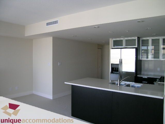 Bright kitchen with dark countertops and white cabinets, open to a spacious living area. - 2801 - 1205 W. Hastings Street, Vancouver Downtown