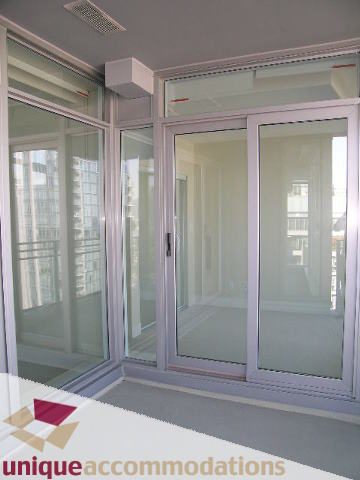 Bright living room with sliding glass doors leading to a balcony, showcasing a city view. - 2801 - 1205 W. Hastings Street, Vancouver Downtown