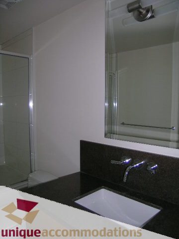 Modern bathroom with black countertops and a sleek sink. - 2801 - 1205 W. Hastings Street, Vancouver Downtown