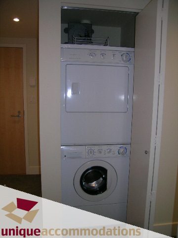 Laundry area with stacked washer and dryer, modern design. - 705 - 1205 W Hastings, Vancouver Downtown