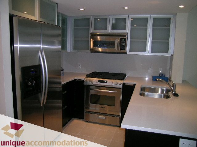 Bright kitchen with stainless steel appliances, white countertops, and modern cabinets. - 705 - 1205 W Hastings, Vancouver Downtown