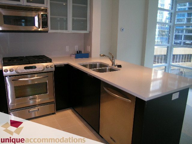Bright kitchen with modern appliances, white countertops, and city view. - 705 - 1205 W Hastings, Vancouver Downtown