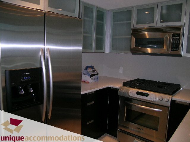 Bright kitchen with stainless steel appliances, black cabinetry, and white countertops. - 705 - 1205 W Hastings, Vancouver Downtown