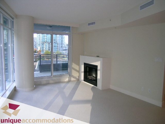 Bright living room with large windows, city view, and modern fireplace. - 705 - 1205 W Hastings, Vancouver Downtown