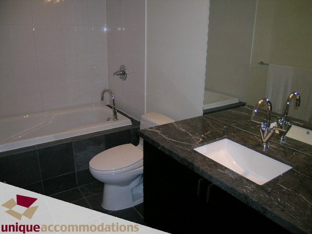 Furnished 1-bedroom condo with dark marble countertops and modern sink. - 705 - 1205 W Hastings, Vancouver Downtown