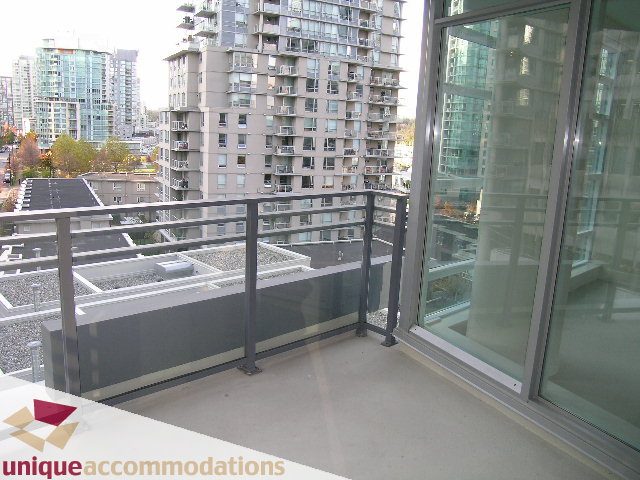 Furnished balcony with glass railings, city view, and modern furnishings. - 705 - 1205 W Hastings, Vancouver Downtown