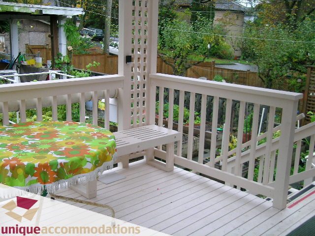 Furnished deck with white railings and floral tablecloth, surrounded by greenery. - 782 W 22nd Ave, Vancouver West Side