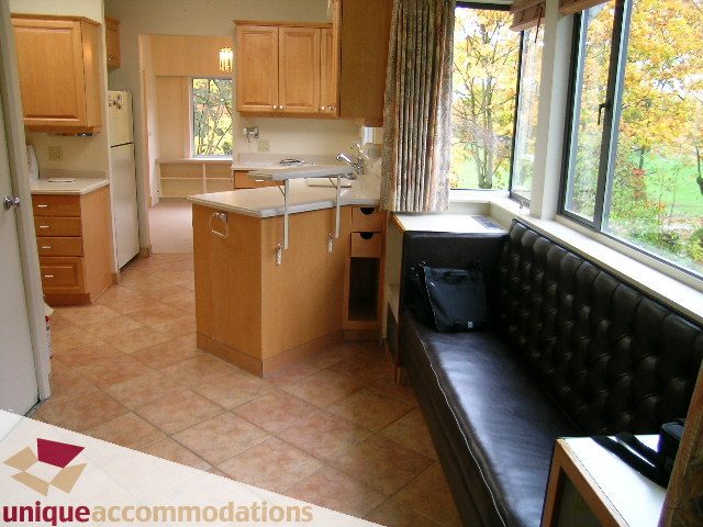 Bright kitchen with granite countertops and a cozy window seat, featuring a view of autumn foliage. - 782 W 22nd Ave, Vancouver West Side