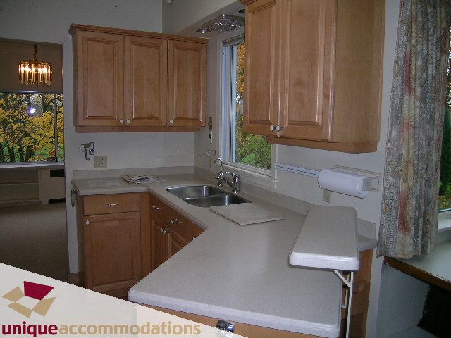 Bright kitchen with light countertops and wooden cabinets, featuring a city view through the window. - 782 W 22nd Ave, Vancouver West Side