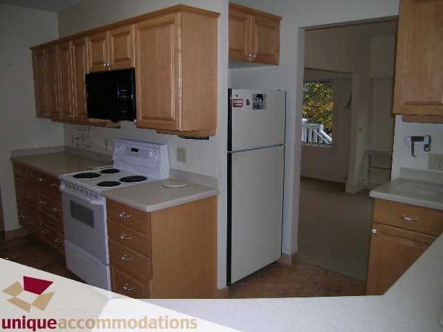 Bright kitchen with light countertops, wooden cabinets, and a city view through the window. - 782 W 22nd Ave, Vancouver West Side