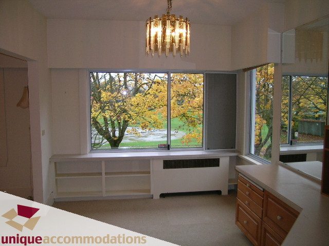 Bright kitchen with white countertops and large windows showing a tree-lined view. - 782 W 22nd Ave, Vancouver West Side