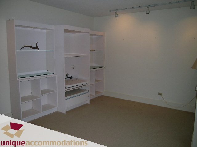 Bright living room with white shelving units and carpeted floor. - 782 W 22nd Ave, Vancouver West Side